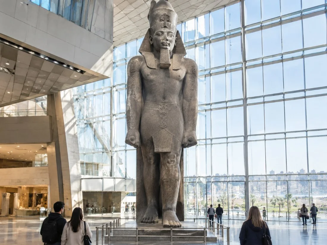 A colossal standing statue of Ramesses II in the bright atrium of the Grand Egyptian Museum
