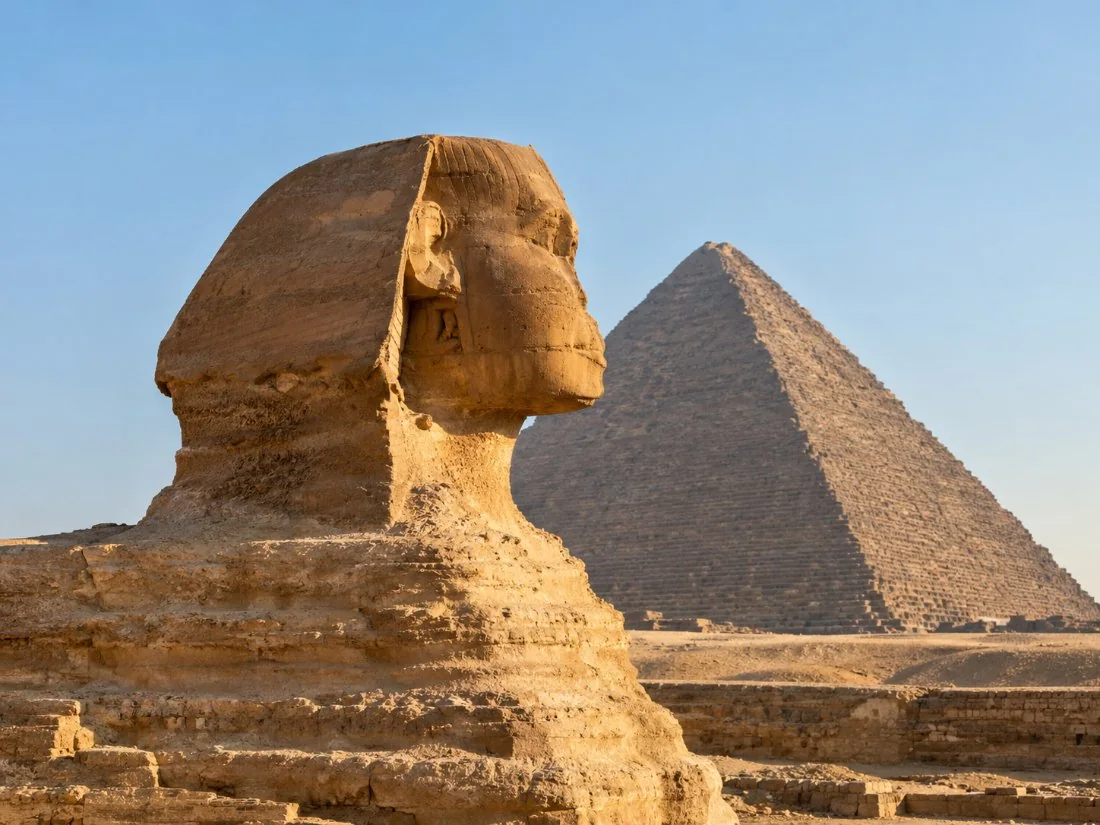 The Great Sphinx of Giza in profile in warm morning light, with the Pyramid of Khafre rising behind it